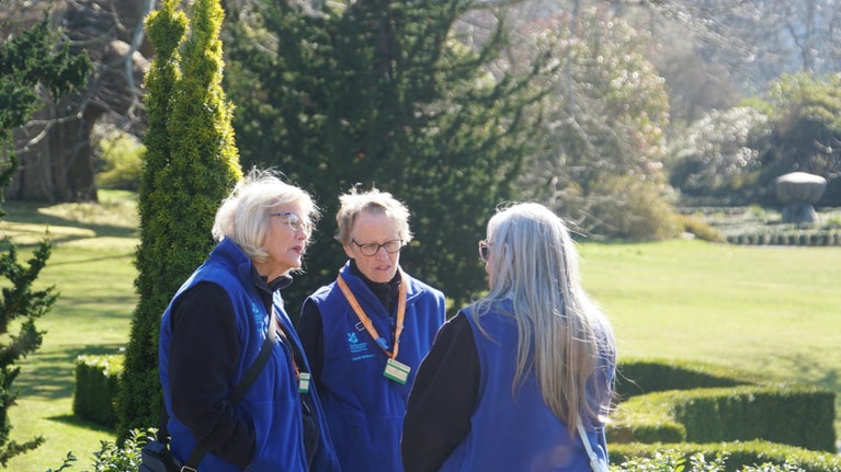 Gwirfoddolwyr yng Ngardd Bodnant, yn ystod y gwanwyn gyda'r ardd tu ôl